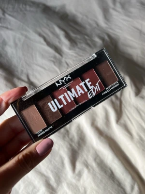NYX Ultimate Edit ögonskuggspalett - NYX Ultimate Edit ögonskuggspalett med sex nyanser i varma toner som beige, brons, rosé, terrakotta och brunt. Paletten har både matta och skimrande skuggor i ett kompakt plastfodral, perfekt att ta med i väskan.