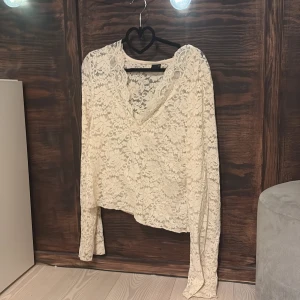 Cream Vit spetsblus från Gina Tricot - Säljer en superfin cream vit spetsblus från Gina Tricot med v-ringning och lång ärm. Blusen har ett romantiskt blommigt spetsmönster och är lätt transparent. Perfekt att styla med ett linne under för en trendig look. Använt fåtal gånger. Inget fel på varan. Jag har vanligt vis storlek xs men denna i storlek xl passar perfekt i längd mm men inte tajt på mig!