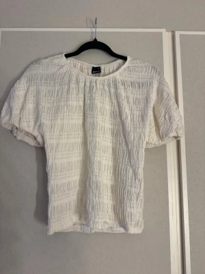 Vit puffärmad topp  - Superfin vit topp med puffärmar och strukturerat tyg. Rund halsringning och avslappnad passform.