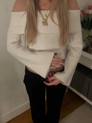 Vit off shoulder tröja med vida ärmar - Trendig vit ribbstickad off shoulder tröja med vida ärmar. Snygg och stilren modell som sitter åt upptill och har en bred kant vid axlarna. Perfekt för dig som gillar en modern och chic look.