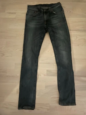 slim fit jeans från Nudie - Snygga mörkblå slim fit jeans från Nudie med klassisk femficksdesign och diskreta slitningar. Jeansen har orange sömmar och Nudie-logga på bakfickorna. Tillverkade i denim med en något stretchig känsla för extra komfort. Helt oanvända jeans pris kn diskuteras vid snabb affär