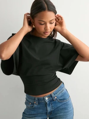 Svart croppad topp med vida ärmar - En svart croppad topp med vida korta ärmar och tight passform runt midjan. T-shirten har en enkel design och är tillverkad i mjukt bomullsmaterial. Perfekt för dig som gillar en stilren och modern look.