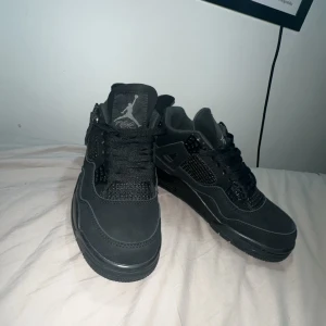 Svarta Jordan 4  - Säljer ett par helsvarta Nike Air Jordans med klassisk siluett och Jumpman-logga på plös, sula och häl. Skorna har snörning och är tillverkade i en mix av skinn och syntetmaterial. Perfekta för dig som gillar stilrena och ikoniska sneakers. Pris kan diskuteras! 