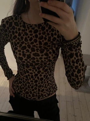 Leopardmönstrad långärmad topp - Snygg långärmad topp med leopardmönster i bruna och svarta toner. Figurnära passform och rund halsringning. Perfekt för dig som vill sticka ut med en trendig och djärv look.