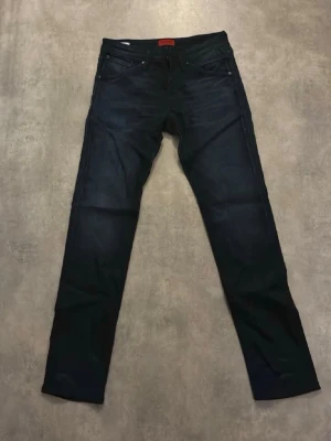Mörkblå slim fit jeans - Snygga mörkblå jeans med slim fit passform och klassisk femficksdesign. Jeansen har en diskret tvätt och raka ben. Perfekta för en trendig och stilren look.