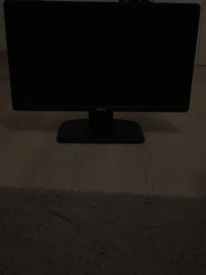 Svart Dell datorskärm - Säljer en svart datorskärm från Dell med stilren, rektangulär form och stabil fot. Perfekt för gaming, plugg eller filmkvällar vid datorn. Skärmen har diskret Dell-logga på framsidan och passar snyggt på skrivbordet.