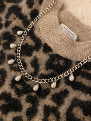 Silverfärgat halsband med pärlor - Snyggt halsband i silverfärgad rostfritt stål med kedja och droppformade vita pärlor som hänger längs hela kedjan. Perfekt för att ge din outfit en trendig och elegant touch.