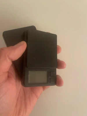 Digital fickvåg i svart plast - Smidig digital fickvåg i svart plast med rektangulär form. Utrustad med liten display och två knappar för enkel användning. Perfekt för att väga småsaker och lätt att ta med sig tack vare kompakt storlek.Fri Frakt 📦 +20kr?