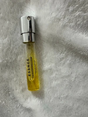 Essnce Carashmellow Eau de Parfum - Essnce Carashmellow Eau de Parfum i en smidig glasflaska med sprayfunktion och silverfärgat lock. Parfymen har en gul vätska och flaskan är cylinderformad, perfekt att ta med i väskan.