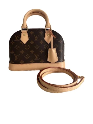 Louis Vuitton Alma BB Monogram väska - Säljer en Louis Vuitton Alma BB handväska i klassiskt monogram canvas med beige läderdetaljer. Väskan har rundad form, två handtag och avtagbar axelrem. Ikoniskt LV-mönster och guldfärgade metalldetaljer och Lv metall lås medföljer. Perfekt storlek för det viktigaste och super fin till din outfit .  Aldrig använd. Lv kartong dustbag och kvitto medföljer.  Säljer den pga mitt ex köpte den till mig. Annars är väskan underbar. Nypris 19000kr i butik.  Kan gå ner i pris vid snabb affär. 