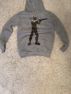 Grå hoodie med snyggt tryck i storlek M passar fin fint - Grå. Hoodien har dragsko i huvan och ribbade muddar vid ärmslut och nederkant. Perfekt för en avslappnad streetstyle-look.