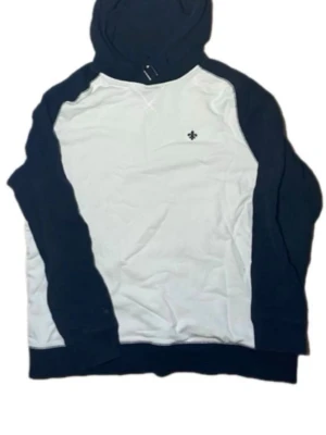 Vit och marinblå hoodie med emblem - Snygg hoodie i vit och marinblå färg med raglanärmar och liten broderad logga på bröstet. Klassisk huva och muddar i ärmslut och nederkant. Perfekt för en avslappnad streetstil. Materialet känns mjukt och bekvämt.