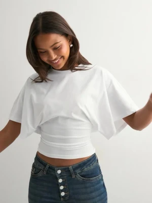 Vit croppad topp med vida ärmar - Snygg vit croppad topp med vida korta ärmar och ribbad midja. Perfekt för dig som vill ha en modern och stilren look. T-shirten har en enkel design och passar till jeans eller kjol. Materialet känns mjukt och bekvämt.