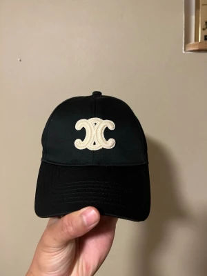 Vintage Celine Svart Keps - Hej, säljer nu en riktig fin keps som är vintage av Celine, guld och beige detaljer med svart färg, passar alla storlekar, har aldrig använts
