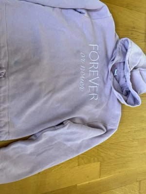 Ljuslila hoodie från Lindex - Säljer en ljuslila hoodie från Lindex med texten 'FOREVER or never' broderad på bröstet. Hoodien har huva och är tillverkad i mjuk bomullsblandning. Perfekt för dig som gillar en avslappnad och trendig stil. 