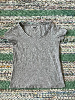 Grå basic t-shirt från 157 - En enkel och stilren grå t-shirt från 157 med rund halsringning och korta ärmar. Tillverkad i en mjuk blandning av bomull, viskos och elastan för skön passform. Perfekt till alla dina outfits och lätt att matcha.