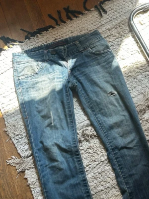 Blå slitna jeans med hål - Säljer ett par blå jeans med slitningar. Riktigt snygga och är i vintage modell. Osäker på storlek men skulle uppskatta runt M