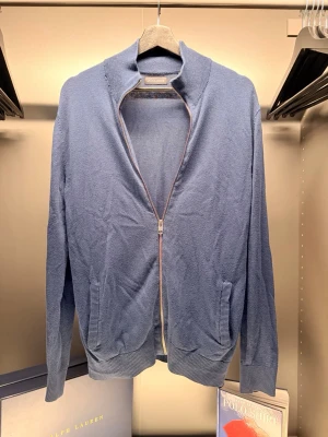 Blå ziptröja från Jack & Jones  - Snygg blå ziptröja i mjukt material. Tröjan har hög krage, dragkedja framtill och två fickor. Ribbstickade muddar vid ärmslut och nederkant ger en clean look. Perfekt att slänga över en t-shirt för en avslappnad stil.