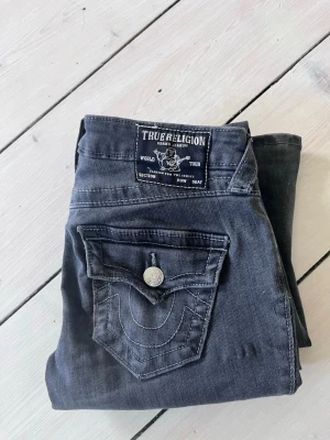  True Religion jeans - Snygga mörkgrå jeans från True Religion💓 storlek w23 som sitter bra på mig som är ca 165cm, bara att skriva om ni vill ha de exakta måtten. Jeansen har lite slitage längst nertill men inget man tänker på👌 