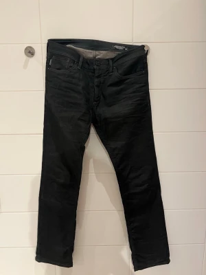 Svarta jeans från Jack and Jones  - Snygga svarta jeans från Jack and Jones  med klassisk femficksdesign och raka ben. Jeansen har normal midja och diskreta sömmar, perfekta för en stilren look. Materialet är denim med en mjuk känsla.
