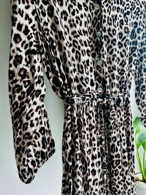Cream CRAlora leopard maxiklänning (S/M) - Supertrendig maxiklänning från Cream (CRAlora Long Dress) i stl S/M. Gjord i Italien av 100% viskos som ger ett lyxigt fall! Skjortmodell med knappar fram, krage, knytband i midjan och volangdetalj i kjolen. Mycket fint skick! Mått plant: Byst: ca 49cm Midja: ca 46cm Axel: ca 39cm Ärm: ca 44cm Längd: ca 127cm