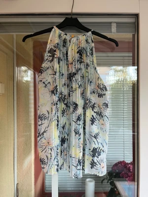 Blommig ärmlös topp från ONLY - Superfin ärmlös topp från ONLY i storlek 34. Toppen har ett blommigt mönster i ljusblått, gult, svart och lite rosa. Den är luftig och har plisserade detaljer. 