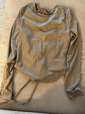 Beige långärmad topp med snörning - Beige grå långärmad topp med snörning baktill. Träningstopp. 