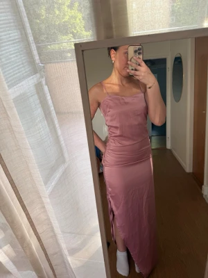 Rosa långklänning med slits - Säljer en elegant rosa långklänning med smala axelband och slits på sidan. 