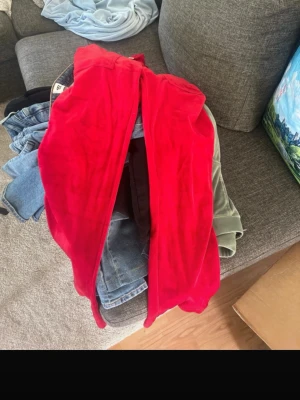 Juciy couture  - Säljer ett par riktigt snygga röda mjukisbyxor i mjuk velour. Byxorna har resår i midjan med dragsko och två fickor framtill. Perfekta för chill dagar eller när du vill vara extra bekväm. Dessa är inte använda 