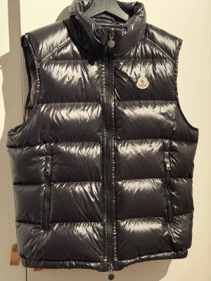 Moncler Bormes Gilet dunväst - Säljer min svarta Moncler Bormes Gilet dunväst i strl 4 (medium M) då den inte längre kommer till användning. Minimalt använd och därav i god skick som ni kan se på insidan stora lappen (brukar gå av vid användning). Har inte kvitto då jag fått den i present. NFC finns på ut- och insidan (lappen). Luvan finns men glömde sätta på den - följer med. Se priset och bedöm själv. Postar helst via plick, men möts även upp (Stockholm). 