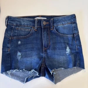 Lågmidjade jeans short - Snygga blå lågmidjade jeansshorts från Pull&Bear med slitna detaljer. Säljer pga för små, mycket bra skick!