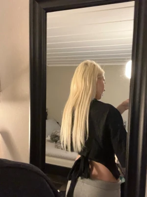 Svart croppad topp med knyt i ryggen - Säljer en svart croppad topp med knyt i ryggen. Toppen har korta ärmar och en tight passform som framhäver midjan. Perfekt för dig som gillar en enkel men snygg stil. Materialet känns mjukt och stretchigt.