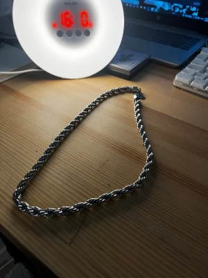 Silverfärgad kedja - Säljer ett stilrent halsband i silverfärg med tvinnad kedja. Halsbandet har en chunky look och passar perfekt för dig som vill ha ett statement piece. Materialet ser ut att vara metall och designen är klassisk rope chain. Inget synligt märke på halsbandet.