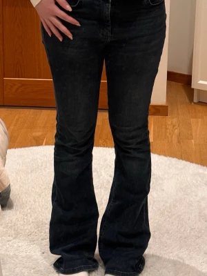 Mörkblå bootcut jeans - Mörkblå bootcut jeans med normal/ låg midja. Jeansen har en utsvängd passform nedtill och är tillverkade i ett stretchigt denimtyg som sitter bekvämt. Storlek M/32