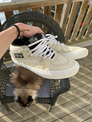 Vans Half Cab - Säljer ett par vita Vans Half Cab sneakers med svart plös och klassisk Vans-logga på sidan. Skorna har vita snören, vit sula och är tillverkade i mocka och textil. Perfekta för dig som gillar streetwear och skate-inspirerad stil. skorna köptes för 1000kr från vans officiella hemsida och är sparsamt använda. (original skolåda ingår)