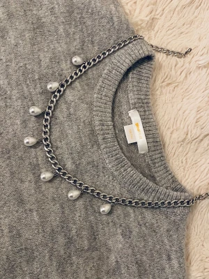 Silverfärgat kedjehalsband med pärlor - Säljer ett trendigt silverfärgat halsband  rostfritt stål med kedja och droppformade pärlor längs hela halsbandet. Perfekt för dig som gillar statement-smycken och vill addera något extra till din outfit. Justerbar längd med karbinlås.