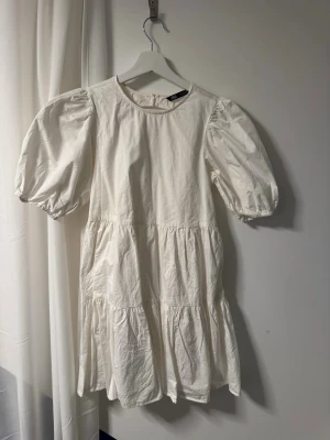 Vit klänning Zara - Supersöt vit kort klänning från Zara med puffärmar och volangdetaljer. Perfekt till sommaren! Endast använd två gånger!