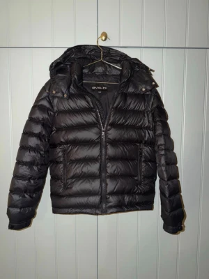 Svart pufferjacka från Evaldi - Svart pufferjacka från Bvaldi med avtagbar huva. XXS! Köpt på väla. Passar dig som är 155-165cm. Svarar snabbt🙏🏼