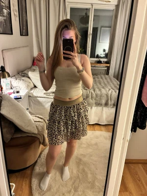 Leopardmönstrad kortkjol med volang - Säljer en leopardmönstrad kortkjol med volang och bred, glittrig guldresår i midjan. Kjolen är luftig och har en cool, ungdomlig stil som passar perfekt till sommarens outfits.