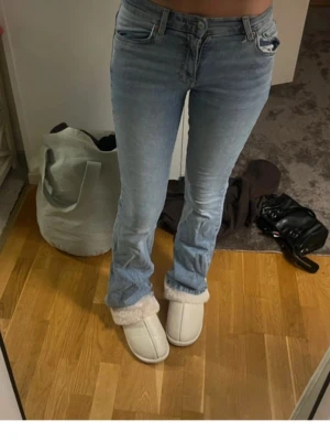 Ljusblå bootcut jeans - Säljer ett par ljusblå bootcut jeans med klassisk femficksdesign och normal midja. Jeansen har en lätt tvättad look och är tillverkade i denim med lite stretch för skön passform. Perfekta för en avslappnad och trendig stil.