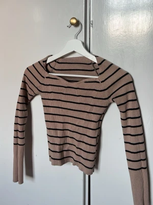 Beige ribbad randig långärmad topp - Trendig ribbad topp i beige med svarta ränder och lång ärm. Toppen har en snygg v-ringad halsringning och är figurnära i modellen. Perfekt att styla med jeans eller kjol för en cool look.😍😍😍