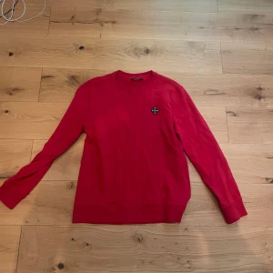 Röd tröja från J.Lindberg - Säljer en snygg röd tröja från J.Lindberg med rund hals och långärmad design. Tröjan har en diskret logotyp på bröstet och är perfekt för både vardag och avslappnade tillfällen. Passar bra till jeans eller chinos. Priset kan diskuteras.