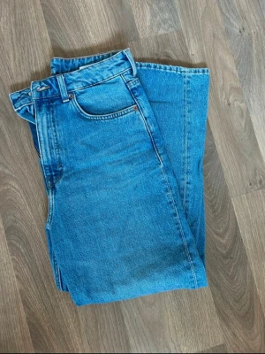 Blå momjeans med hög midja från Weekday - Säljer ett par blå jeans med rak passform och hög midja då dom är för stora. Från Weekday, modellen ”Meg”. Storlek 29/28. 