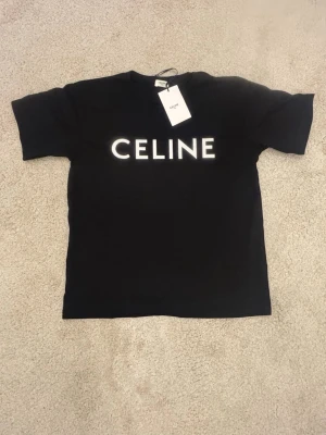 Svart t-shirt från Cline - Svart t-shirt från Cline med klassisk vit logotyp framtill. T-shirten har rund halsringning och korta ärmar. Perfekt för en stilren och trendig look.