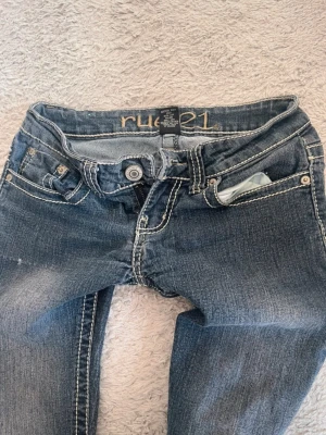Blå bootcut jeans från rue21 - Jättesnygga lågmidjade utsvängda jeans, perfekta året runt🌸  Storlek på etikett: 0/1, känns som W25 L28. Stretchigt material över låren och I midjan.  Midja tvärs över: 34cm Midjehöjd: 16cm Innerbenslängd: 73cm Benvidd nedtill: 21cm