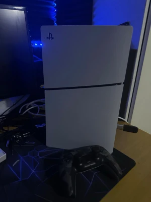 PlayStation 5 med handkontroll - PlayStation 5 konsol i vit färg med svart detalj i mitten. Snygg och modern design med rundade kanter. Medföljer en svart DualSense handkontroll. Perfekt för gaming och nya spelupplevelser.