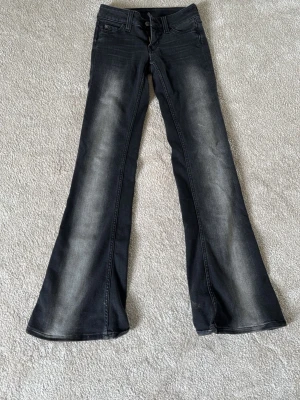Svarta bootcut jeans med slitningar - Säljer ett par svarta bootcut jeans med snygga slitningar och tvättade detaljer längs benen. Jeansen har klassisk femficksmodell och normal midja. Perfekta för dig som gillar en retro och avslappnad stil.