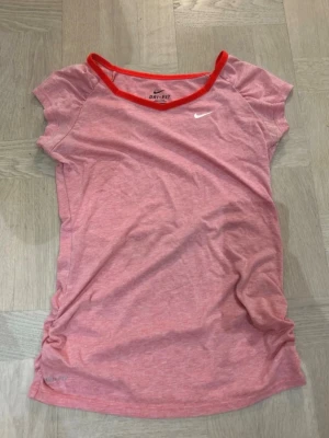 Nike t-shirt - Snygg rosa sport-t-shirt från Nike med Dri-FIT-material som andas. T-shirten har korta ärmar, rund hals med röd kant och en liten vit Nike-logga på bröstet. Perfekt för träning eller löpning.  Det står storlek M, men den passar mer som xs.💖