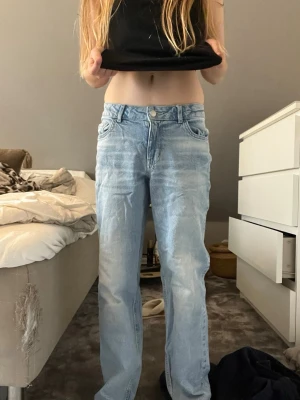 Ljusblå raka jeans i denim - Säljer ett par ljusblå jeans med rak passform och klassisk femficksdesign. Jeansen har normal midja och är tillverkade i denim med en lätt tvättad look. Perfekta för en avslappnad och trendig stil.