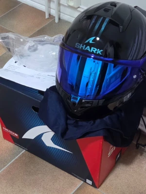 Svart motorcykelhjälm Shark S - Nyskick! Säljer min Shark Ridill 2 Assya (stl S, 55-56 cm) inköpt 2025-06-22. Använd endast ett fåtal gånger. Senaste säkerhetsklassen ECE 22.06.Detta ingår:• Monterat Blue Iridium-visir (nypris 900kr)• Original klart visir (oanvänt)• Kvitto & originalkartong• 5 års garanti från inköpsdatum. Hjälmen har integrerat solvisir. Skyddspåse till hjälmen ingår också. Aldrig tappad eller krockad. Nypris totalt: 2 968 kr.